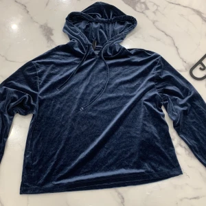 Mörkblå sammetshoodie från märket Pieces - Snygg och bekväm mörkblå hoodie i sammet från märket Pieces. Perfekt för en avslappnad stil med sin mjuka känsla och klassiska design. Hoodien har långa ärmar och en justerbar huva med dragsko.