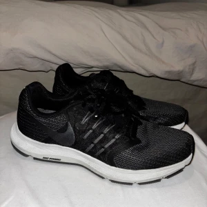 Svarta Nike Run Swift sneakers - Säljer ett par svarta Nike Run Swift sneakers med vit sula och snörning. Perfekta för löpning och träning med en stilren design och bekväm passform.