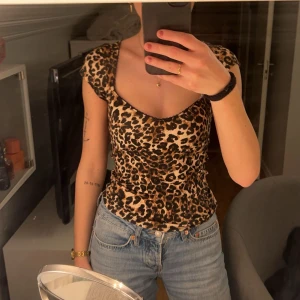 Leopardmönstrad topp från Nelly - Säljer en snygg leopardmönstrad topp från Nelly. Toppen har en v-ringad design och korta ärmar, perfekt för en trendig look. Den är i en tight passform och tillverkad i ett mjukt material. Den är i storlek xxs men passar även mig som vanligvis bär s! Den är endast testad!
