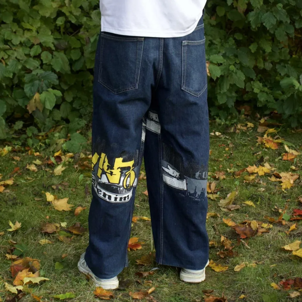 Säljer ett par coola baggy jeans med graffiti-inspirerat mönster i gult och vitt. De har en loose fit och är perfekta för en avslappnad streetwear-look. Jeansen är mörkblå och har klassiska femfickor. Perfekta för höst och vår!. Jeans & Byxor.