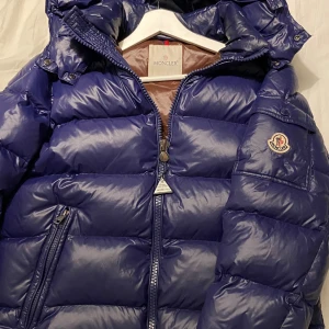 Monlcer maya - Hej säljer nu min exkusiva moncler maya jacka med en sällsynt blå/lila färg. Triangelns färg har slitits bort lite men annars är jackan fel fri, priset kan ändras minimalt. Jag är 186 och passar mig perfekt och den är storlek 2/M!😇