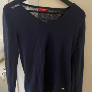 Mörkblå tröja med spetsdetaljer från Guess - Säljer en mörkblå tröja från Guess med v-ringning och fina spetsdetaljer. Står storlek M men skulle säga att den sitter mer som en S. Aldrig använd av mig men köpt på Sellpy. Superfin och i bra skick!