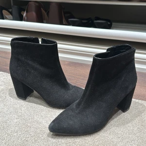 Svarta mocka boots från Vagabond - Snygga svarta boots i mocka från Vagabond med spetsig tå och klack. Perfekta för både vardag och fest. De har en dragkedja på sidan för enkel på- och avtagning. Stilrena och bekväma, dessa boots är ett måste i garderoben!