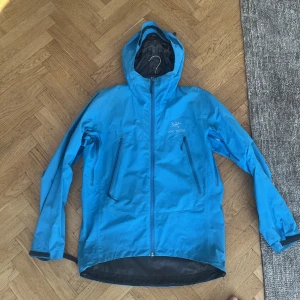 Arcteryx Alpha  - Tvär fet jacka! Sitter ett litet 1 cm hål vid vänster ficka men går ej rakt igenom utan bara första lagret så påverkar ej regntätheten!