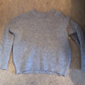 Grå stickad tröja - Säljer en mysig grå stickad tröja i bra skick. Perfekt för kyliga höst- och vinterdagar. Tröjan har långa ärmar och en klassisk rund halsringning. Den är superbekväm och passar till det mesta i garderoben!