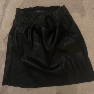 Svart kjol från Zara - Säljer en snygg svart kjol i fejkskinn från Zara, storlek small. Kjolen har en elastisk högre midja & fickor i sidorna🖤Så fin nu med fina strumpbyxor och stickad tröja 🥰