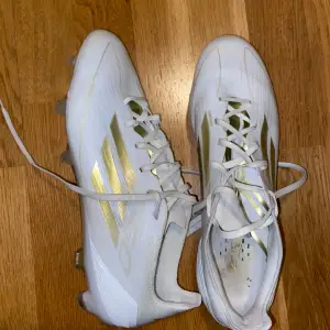 Säljer ett par snygga vita fotbollsskor med guldiga detaljer. De har snörning och är i mycket bra skick. Perfekta för fotbollssäsongen! Adidas F50 pro FG Day Spark - vit/guld