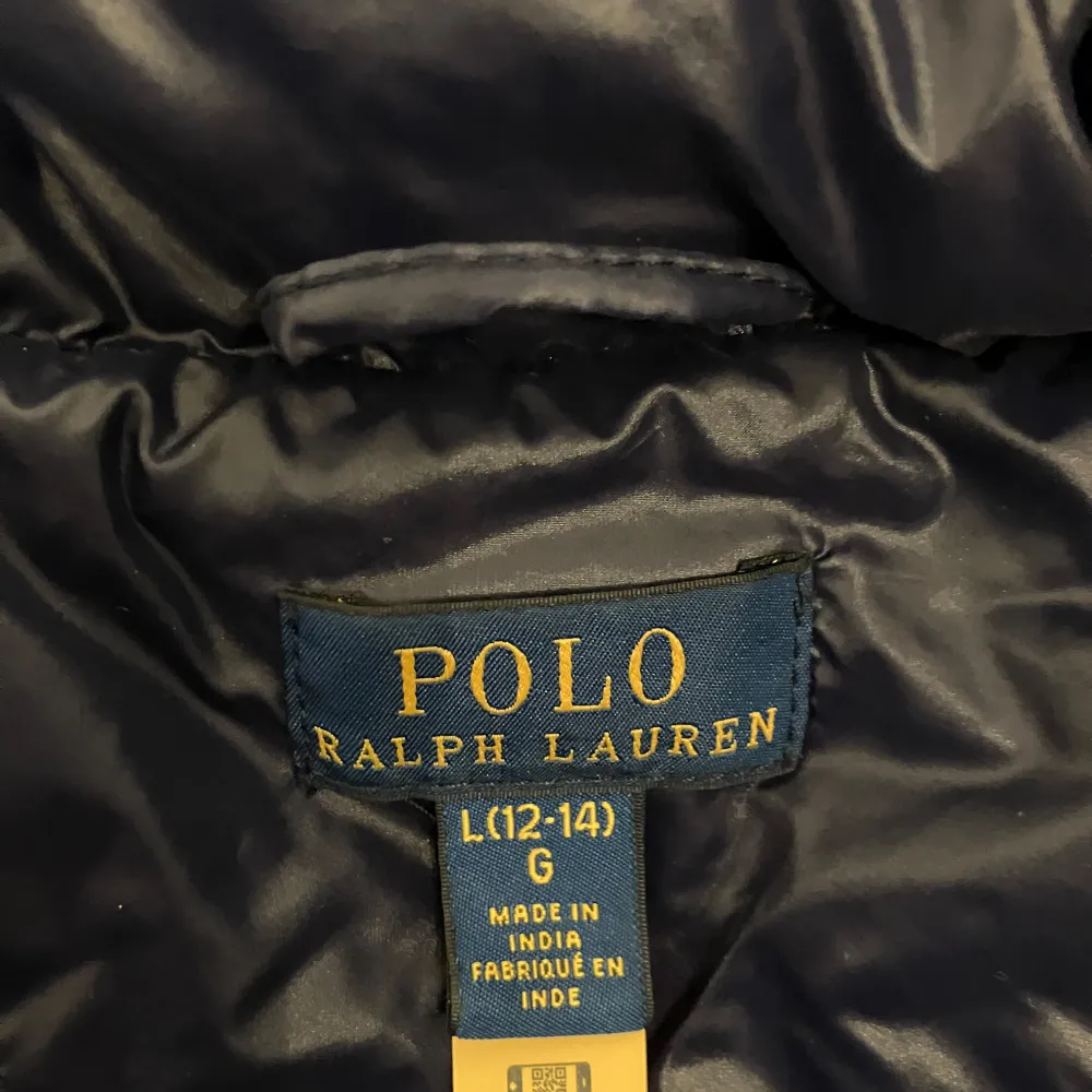 Säljer en snygg mörkblå dunjacka från Polo Ralph Lauren. Den är perfekt för kalla vinterdagar med sin tjocka vaddering och huva. Jackan har en dragkedja framtill och två praktiska fickor. Den är i mycket bra skick och redo för nya äventyr! Storlek 12-14 år liten i storleken så mer 10-12 år. Frakt ca 70 kr.. Jackor.