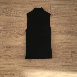 Svart polotopp - Snygg svart ärmlös polotopp från New Yorker i ribbat material. Perfekt för lager-på-lager eller att bära som den är. Passar både till vardags och festliga tillfällen. Toppen är i mycket bra skick och redo för en ny garderob!