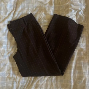 Bruna kritstrecksrandiga kostymbyxor - Köpta på second hand i Danmark och sitter baggy och midwaist på mig som normalt är en s/m i byxor. Jag är 174 och de nåt ner över skorna på mig! 