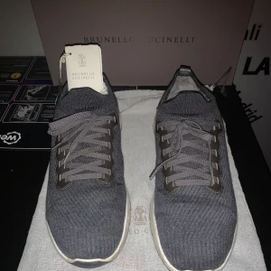 Grå sneakers från Brunello Cucinelli - Säljer ett par snygga grå sneakers från Brunello Cucinelli i mycket bra skick. De har en stilren design med snörning och en bekväm sula. Perfekta för både vardag och festliga tillfällen. Kommer med originalförpackning och dustbag. Litet hål se sista bild.