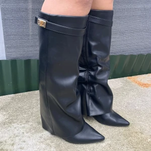 Svarta boots - Snygga svarta stövlar i skinn med spetsig tå och dekorativt bälte upptill. Perfekta för höst och vinter, dessa stövlar har en elegant design som passar både till vardags och fest. De har en dragkedja på sidan för enkel på- och avtagning. Endast använda en gång och är i storlek 40 men passar mig med lite bredare fötter som vanligtvis har 38!