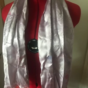 Ljuslila silkesjal med Eiffeltornet-motiv - Säljer en elegant ljuslila silkesjal med ett subtilt Eiffeltornet-motiv. Perfekt för att ge en touch av Parisisk stil till din outfit. Sjalens mjuka material gör den skön att bära och den passar bra till både vardag och fest. Har några fläckar. Kan mötas upp i Helsingborg eller skickas. 