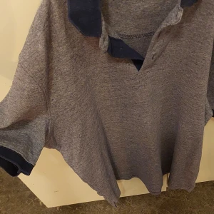 Grå pikétröja från Splash - Säljer en grå pikétröja från Splash i storlek L. Tröjan har en klassisk krage i mörkare nyans och korta ärmar. Perfekt för en avslappnad stil eller en dag på golfbanan. Skön och enkel att matcha med jeans eller shorts.