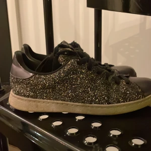 Glittriga sneakers från Victoria - Säljer ett par glittriga sneakers från Victoria i svart och silver. De har snörning och en bekväm passform. Perfekta för att lysa upp vardagen eller en festkväll! Skorna är i bra skick med lite slitage på sulan.