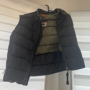 Svart dunväst Äkta Parajumper - Säljer en svart dunväst från Napapijri i mycket bra skick. Västen har en dragkedja framtill och är perfekt för höst och vår. Den är quiltad och ger en skön värme utan att vara för tung. Passar bra till både vardag och lite mer avslappnade tillfällen. Passar både S/M. Köpt 300kr
