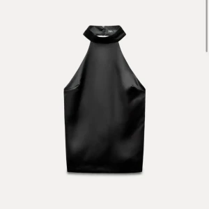 Svart ärmlös topp från Zara - Snygg svart ärmlös topp från Zara i ett glansigt material. Perfekt för en utekväll eller fest. Den har en hög krage och en stilren design som ger en elegant look. Passar bra till både kjol och byxor. Toppen är inte ljust denna, fanns ingen bild som jag hitta men ser exakt lika ut framifrån. Baktill är den stängd i ryggen med ett knäppe 