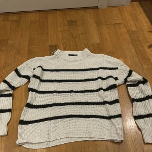 Vit och svart randig stickad tröja från 157 - Säljer en snygg vit stickad tröja med svarta ränder från 157. Den har en avslappnad passform och är perfekt för både höst och vinter. Tröjan är långärmad och supermysig att ha på sig. Lite nopprig, men inte mycket