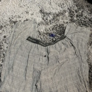 Rutig byxa från Calvin Klein - Snygga rutiga byxor från Calvin Klein med elastisk midja och märkets logga på resåren. Perfekta för en avslappnad stil med en klassisk touch. Byxorna har en bekväm passform och är tillverkade i ett mjukt material.