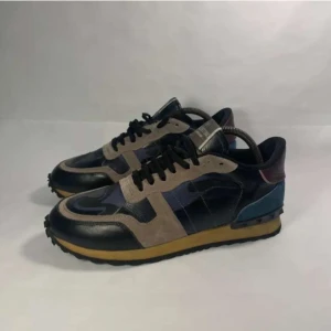 Valentino rockrunners - Snygga Valentino Garavani sneakers med en mix av färger som svart, beige och blå. Skorna har en robust gummisula och är tillverkade i en kombination av skinn och mocka. De har klassisk snörning och en stilren design som passar perfekt för en trendig look. Fråga på vid frågor. //Tom🥂