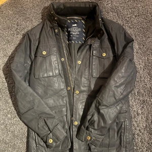 Svart fieldjacka Bondelid - Säljer en stilren fieldjacka från Bondelid. Hängöglan har lossnat i ena fästet, förutom det är jackan i bra skick.