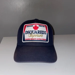 Marinblå keps från Dsquared2 - Snygg marinblå keps från Dsquared2 med broderad logga framtill och texten 'Family Business' baktill. Den är riktigt liten i storleken