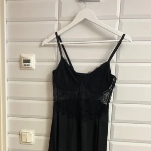 Svart klänning med spetsdetaljer från SHEIN. Storlek:L - Elegant svart klänning med smala axelband och vackra spetsdetaljer över bysten. Perfekt för en stilren look med en touch av romantik. Klänningen har en figurnära passform och är tillverkad i ett mjukt material som faller fint. Aldrig använd. Säljer för 125 kronor. 