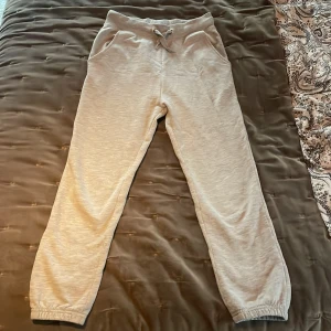 Beige mjukisbyxor - Säljer ett par bekväma beige mjukisbyxor med resår i midjan och vid bensluten. Byxorna har snörning i midjan för justerbar passform och är perfekta för en avslappnad stil.