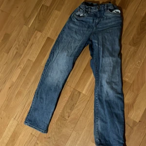 Blå jeans från LAB Industries - Snygga blå jeans från LAB Industries med klassisk femficksdesign och knappgylf. Perfekta för en avslappnad stil. Märkesdetaljer på baksidan ger en extra touch.