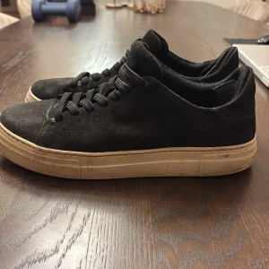 Svarta sneakers från Selected Homme - Snygga svarta sneakers från Selected Homme med en stilren design. Skorna har en ovandel i mocka och en vit sula som ger en klassisk look. Perfekta för en avslappnad stil.