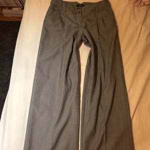 Grå kostymbyxor med knappar - Så snygga kostymbyxor som är lågmidjade och utsvängda!!❤️ De är i storlek S och i väldigt bra skick! Skriv om du har frågor eller vill ha fler bilder❤️❤️