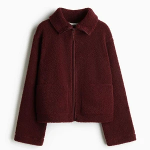 Ny Vinröd teddyjacka pilejacka storlek M från H&M - Ny och oanvänd med tags. Mysig vinröd teddyjacka med dragkedja framtill. Jackan har en normal passform och långa ärmar, perfekt för kyligare dagar. Den har en enkel design med två fickor framtill och en mjuk krage. Storleken är M (inte oversized. Något liten i storlek.