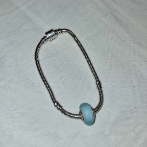 Silverarmband med blå berlock från Pandora  - Elegant silverarmband med en ljusblå berlock. Armbandet har en stilren design med en enkel låsning. Pris går alltid att diskutera💕