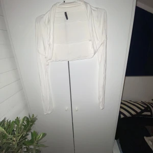 Vit bolerotopp från Amisu - Säljer en stilren vit bolerotopp från Amisu. Perfekt för att lägga till en extra touch till din outfit. Den har långa ärmar och är tillverkad i ett otroligt mjukt och skönt material som inte känns långt ifrån ett äntra hudlager.👍