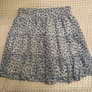 Blommig kjol  - Blommig kjol från New yorker i blått och vitt. Kjolen har en volangdetalj och elastisk midja för en bekväm passform. Perfekt för en somrig look! I ett fint skick ⭐️storlek s