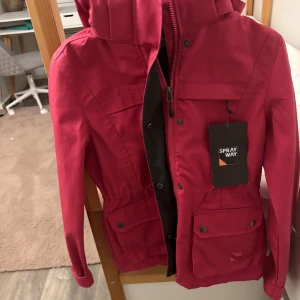 Röd vindjacka från Sprayway kan sänka priset det är bara att kontakta men inte under 365 - Snygg röd vindjacka från Sprayway med huva och dragkedja. Jackan har flera praktiska fickor med knappar och en stilren design. Perfekt för blåsiga dagar.