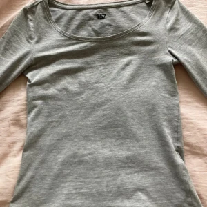 Grå långärmad topp från 157 - Säljer en stilren grå långärmad topp från 157 i mjukt bomullsmaterial. Rund halsringning och tillverkad i en blandning av bomull, viskos och elastan för extra komfort.