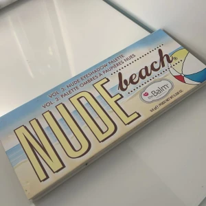 Nude Beach Ögonskuggspalett från theBalm - Snygg ögonskuggspalett med 12 olika nyanser i varma och neutrala toner. Perfekt för att skapa både naturliga och dramatiska looks. Paletten har en spegel och en praktisk dubbelsidig borste för enkel applicering. (Oanvänd)