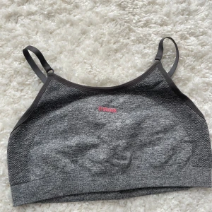 Grå sporttopp från Gymshark stl S - Snygg grå sporttopp från Gymshark med justerbara axelband och rosa logga på baksidan stl S. inlägg medföljer ej, köparen betalar frakt☺️