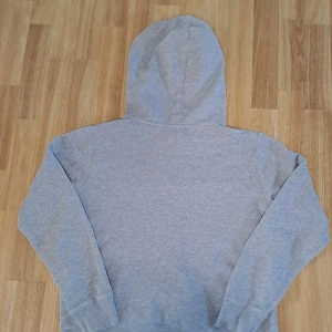 Grå hoodie från Ralph Lauren - Säljer en stilren grå hoodie från Ralph Lauren med det klassiska logotypbroderiet på bröstet. Tröjan har en bekväm passform med långa ärmar och en praktisk huva. Perfekt för en avslappnad look.