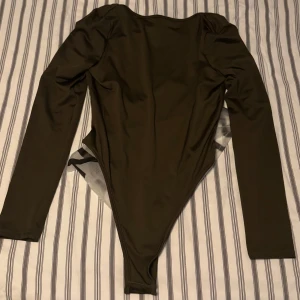 Nytt! Olivgrön bodysuit från Shein storlek M  - Snygg olivgrön bodysuit från Shein i ett stretchigt material. Den har långa ärmar och en djup rundad halsringning. Perfekt för att styla med jeans eller kjol för en trendig look. Är i normal storlek och rirkigt skön kvalité! 