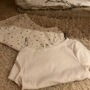 Två vitta ribbade toppar från H&M - Säljer två vitta ribbade toppar från H&M. Topparna har korta ärmar och en enkel design som passar perfekt till vardags. De är mjuk och bekväm att bära.