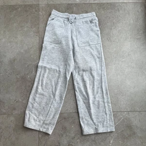 Grå mjukisbyxor med fickor - Säljer ett par bekväma grå mjukisbyxor med elastisk midja och snörning. Byxorna har raka ben och praktiska fickor både fram och bak. Perfekta för en avslappnad stil.