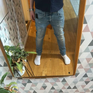 Ljusa jeans från Replay - Snygga ljusa jeans från Replay med slitna detaljer. Byxorna är knappt använda och är i mycket bra skick. De har en Slim passform som ger en modern look. Perfekta för en avslappnad stil.