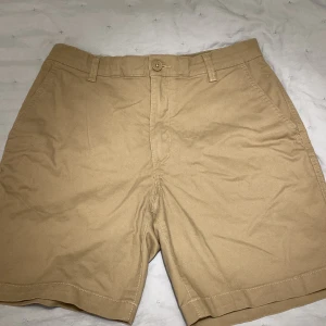 Beige shorts från H&M - Säljer ett par stilrena beige shorts från H&M. De har en klassisk design med knapp och dragkedja framtill samt hällor för skärp. 