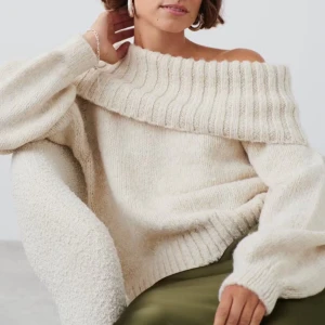 Beige offshoulder stickad tröja - Säljer en mysig beige stickad tröja med offshoulder-design. Tröjan har långa ärmar och en bred ribbad kant vid halsen som ger en stilren look. Perfekt för kyliga dagar. skriv för frågor eller egna bilder💗💗