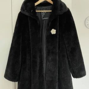 Svart pälsjacka från Steilmann - Elegant svart pälsjacka från Steilmann med en stilren design. Jackan har en klassisk krage och stängs med diskreta hakar. Perfekt för att hålla värmen under kyliga dagar. Det är inte riktigt päls. Vakum påse medföljer. Storlek 42 