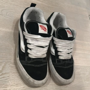 Svarta sneakers från Vans - Säljer ett par klassiska svarta Vans sneakers med vit sula och snörning. Skorna har den ikoniska vita sidostripen och röd logga på plösen. Perfekta för en avslappnad stil.