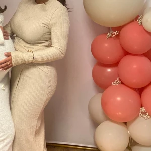 Beige ribbad klänning - Snygg beige ribbad klänning med lång ärm och slits och en elegant detalj i midjan. Perfekt för en stilren look.