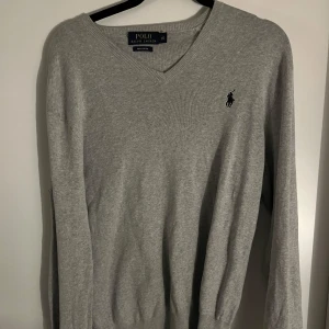 Grå tröja från Ralph Lauren - Snygg grå tröja från Ralph Lauren med v-ringad hals. Storlek Xs i amerikansk storlek vilket motsvarar S/M. Toppen skick inga defekter alls. Hör av er vid andra frågor eller funderingar! 